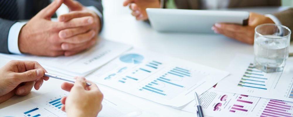 Image of business documents, pen and glasses on workplace during meeting of partners