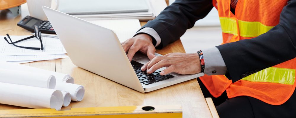 Cropped image of engineer working on laptop in his office